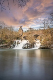 Beautiful landscape in winter with ice and snow. Waterfall of the river Elz near the castle