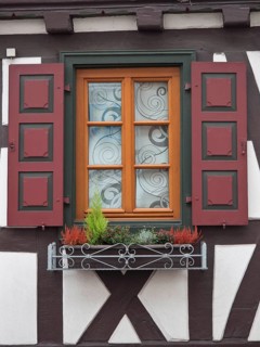 Close-up of a window with red shutters and decorative flower box of a half-timbered house, kandel,