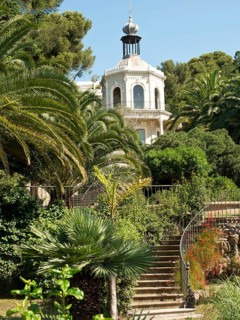 A magnificent villa surrounded by lush gardens and palm trees under a clear sky, la seyne sur mer,