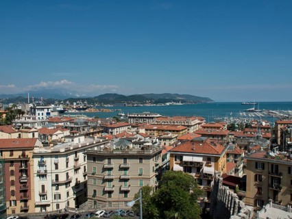 Panoramic view of a coastal town with rooftops, harbour and boats under a blue sky, Bari, Italy,