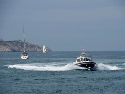 Boats on the sea, waves crashing against rocks under a blue sky, Marseille on the Mediterranean Sea