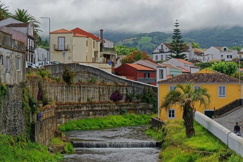 An idyllic village with colourfully painted houses, through which the Ribeira Grande river flows,