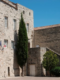 Historic stone building with cypress and flags, under a sunny sky, Provence, le Castellet, France,
