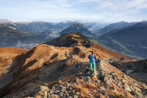 Mountaineer on Kreuzjoch summit, view of Tschirgant summit and the Oberinntal and Pitztal valleys,