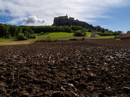 Clods of earth in farmland, Riegersburg Castle in the background, near Riegersburg, Styria,