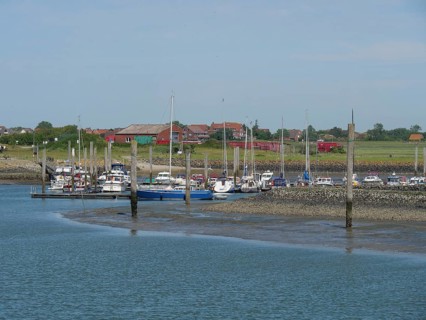Harbour with many boats moored at jetties, surrounded by a picturesque landscape, Baltrum Germany