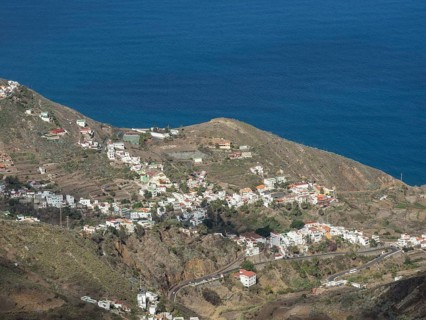 Panorama of a coastal village with houses on rolling hills and the ocean in the background, the