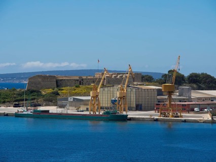 A harbour with cranes and ships, surrounded by buildings and a clear sky, palma de Majorca on the