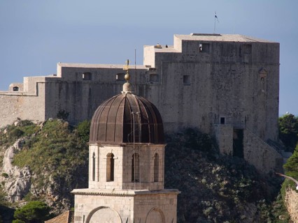 View of a fortress and a church with a dome on a rocky, green hill, the old town of Dubrovnik with