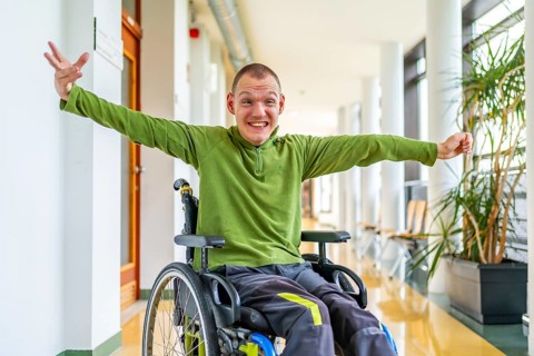 Caucasian adult man with cerebral palsy stretching arms celebrating he is in the university