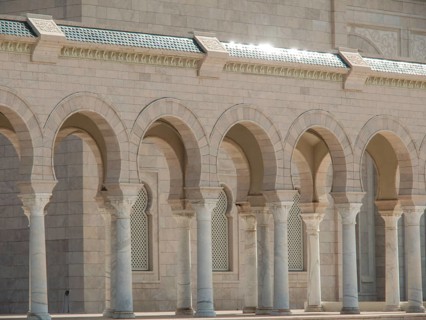 A sun-drenched building with marble columns and arcades that hints at historical significance,