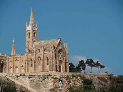 A gothic church with pointed towers and blue skies, majestically built on a rock, the island of
