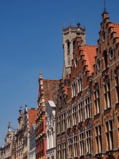 Row of historically decorated gabled houses under a bright blue sky, historic house facades in a