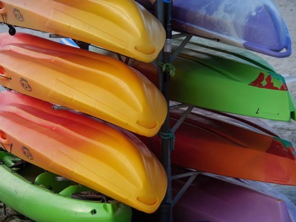 Colourful kayaks are stacked on top of each other and stored on a beach, Baltrum Germany