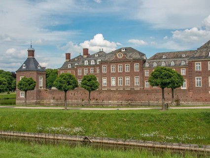 Historic brick castle with manicured lawn and trees under a cloudy sky, historic castle with a