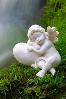 Porcelain angel figurine on moss by a waterfall
