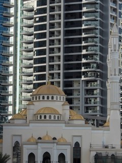 A mosque with golden domes against a backdrop of modern skyscrapers on a sunny day, dubai, arab