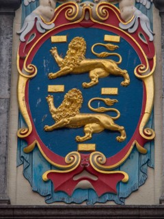 Close-up of a coat of arms with golden lions and colourful decorations, historic houses in Hoorn