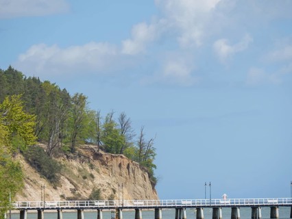 A long bridge stretches along high cliffs and flows into the sea, spring on the Baltic Sea beach in