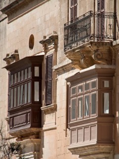 Two balconies made of wood and iron on a historic facade, the town of mdina on the island of malta