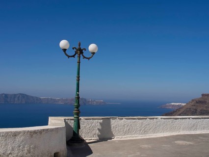 Street lamp on a white terrace with a view of the sea and mountains in the background, The volcanic