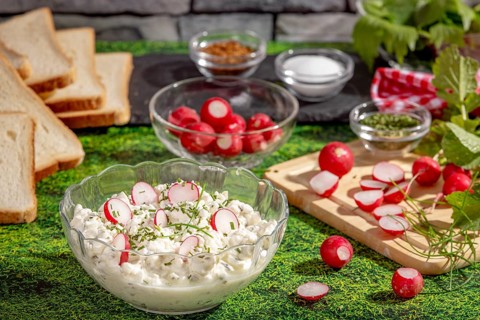 Fresh spread of radishes, cottage cheese and spices surrounded by ingredients and slices of bread
