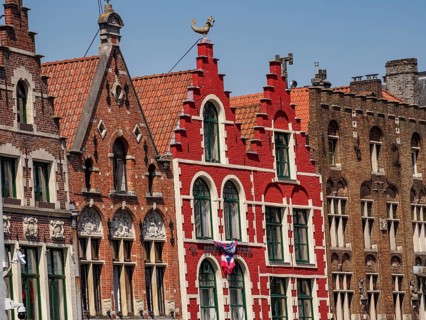 Row of colourful historic houses with gabled roofs and large windows under a clear blue sky,