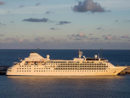 A cruise ship named Silver Spirit in the harbour at dusk, illuminated by the setting sun,