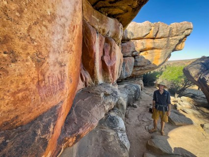 Young man looking at prehistoric depiction of woman on a rock, San rock paintings, Sevilla Art Rock