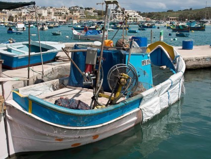 A fishing boat with various items of equipment in the harbour, many colourful fishing boats in a