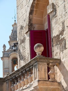 Close-up of historic architecture with red shutters and church tower in the background, the town of