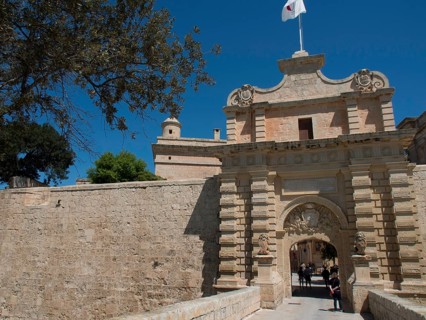 Large sandstone city gate with visitor access and historic charm under a blue sky, the town of