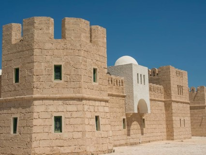 Stone fortress with high walls and towers under a clear blue sky, medieval ambience, Tunis in