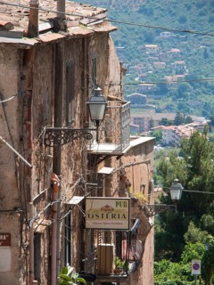 Narrow tram in the old town, lamps and signs for a restaurant, nature and mountains in the