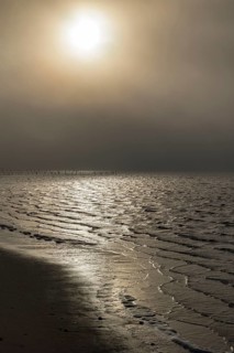 Morning sun shining through the dense fog reflecting on the waters of the Biloxi Bay at Front Beach