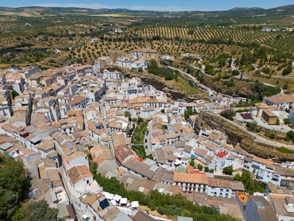 Aerial view of a picturesque town on a hill with serpentine roads and surrounding fields in summer,