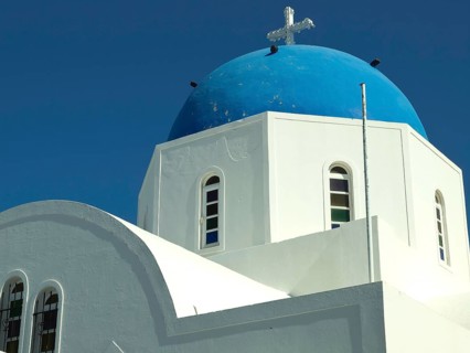 White church with blue dome and cross in front of a clear blue sky, The volcanic island of