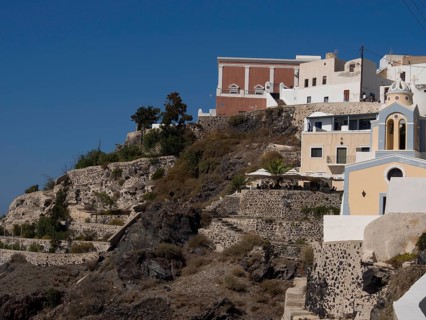Houses and terraces clinging to the cliffs under a blue sky, The volcanic island of Santorini with