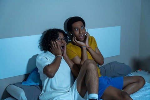 Gay couple watching a scary horror movie at night sitting at home