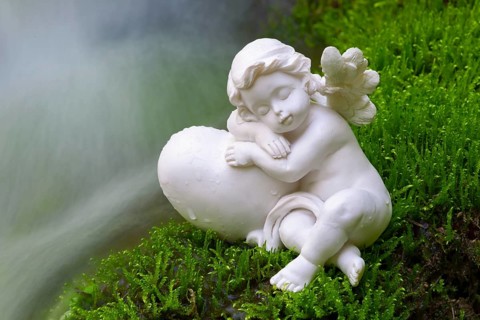 Porcelain angel figurine on moss by a waterfall
