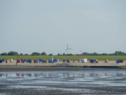 View of a coastal landscape with colourful beach chairs and wind turbines, Baltrum Germany