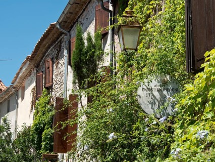 Stone walls with ivy-covered walls, lantern and sign in sunny weather, historic stone houses