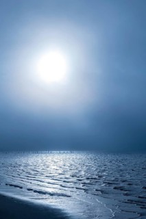 Morning sun shining through the dense fog reflecting on the waters of the Biloxi Bay at Front Beach