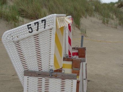 Side view of a beach chair with the number 577 on the sandy beach next to the dunes, Baltrum