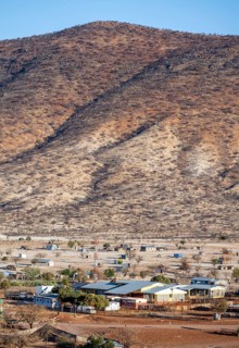 Dry red and white hills in the evening light, houses in the village of Epupa, Kaokoveld, Kunene,