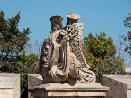 Stone sculpture of an eagle with outstretched wings in a natural setting with trees, the town of