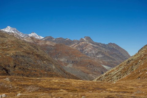 Vast valley between rocky mountains and mountain range under a bright blue sky, bare mountain peaks