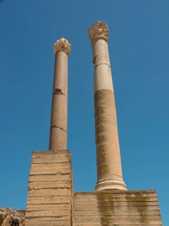 Two tall ancient columns in front of a clear blue sky, part of a ruined site, Tunis in Africa with