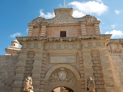 Monumental archway with lion statues, elegant sculptures and historic stone walls under a blue sky,