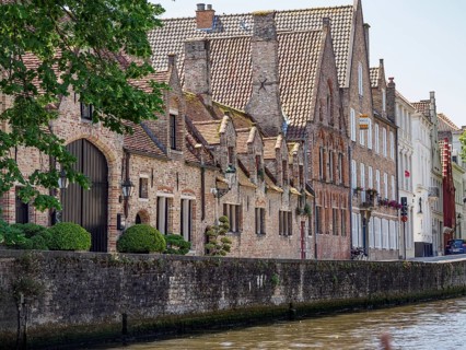 Historic buildings on the canal with decorative gables and green trees, historic city on the river